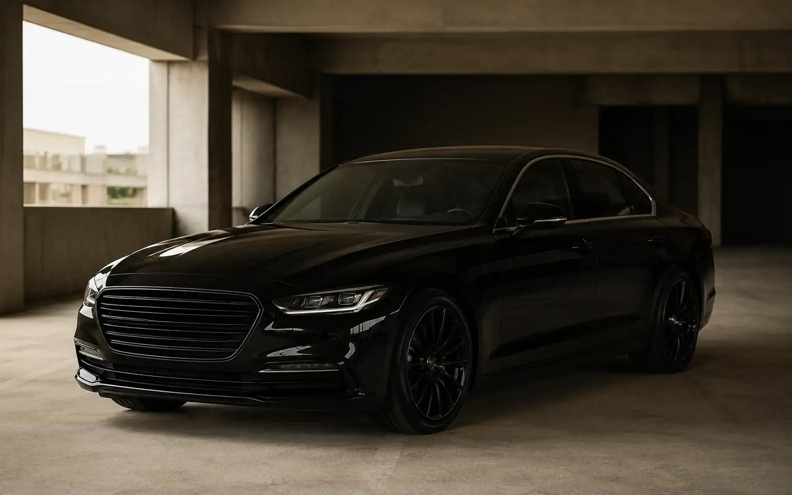 A black executive sedan in a concrete parking structure, lit by soft daylight.